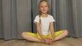 Young girl do yoga butterfly pose. White girl stretchin at living room indoors.