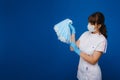 A young girl doctor in a medical mask holds a lot of masks in her hands. A nurse with white masks on a blue background