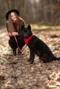 Young girl with a dog walking in the autumn park. Girl has a beautiful black hat Royalty Free Stock Photo