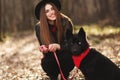 Young girl with a dog walking in the autumn park. Girl has a beautiful black hat Royalty Free Stock Photo