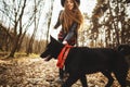 Young girl with a dog walking in the autumn park. Girl has a beautiful black hat Royalty Free Stock Photo