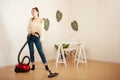 A young girl doing cleaning in the house. A woman vacuums the floor with a vacuum cleaner. Copy space. Listens to music Royalty Free Stock Photo
