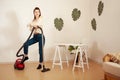 A young girl doing cleaning in the house. A woman vacuums the floor with a vacuum cleaner. Copy space. Listens to music Royalty Free Stock Photo