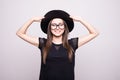 Young girl doing emotion. Dressed in a black shirt, black hat, glasses.