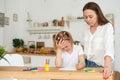 Young girl doing homework during extra-curricular classes with a tutor. Frustrated young mother or tutor teaching kid at