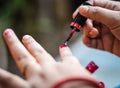 young girl doing nail polish on nails at day in details