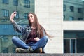 Young girl doing selfie on the background of an office building