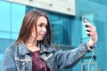 Young girl doing selfie on the background of an office building