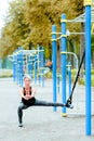 Young girl doing lunge to the side in the park. Uses TRX