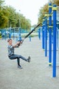 Young girl doing sports on a playground using slings, TRX loop