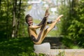 Young girl doing strength gymnastic exercises workout in a beautiful suit outdoors in a park.