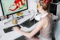 A young girl draws on a PC using a graphics tablet in her comfortable home office. Royalty Free Stock Photo