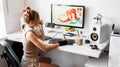 A young girl draws on a PC using a graphics tablet in her comfortable home office. Royalty Free Stock Photo