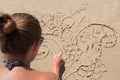 Young girl draws on the sand on the beach a zentangle, doodle.