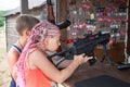Young girl with dreds shoots with gun in shooting range, brother standing by side Royalty Free Stock Photo