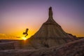 Young girl in a dress jumping near a cliff in a desert during sunset in Las Bardenas Reales, Spain