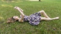 A young girl in a dress lies on the green grass with a phone in her hands. Royalty Free Stock Photo