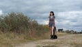 A young girl in a dress and old boots steps along a country road on a cloudy day Royalty Free Stock Photo