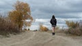 A young girl in a dress and old boots steps along a country road on a cloudy day Royalty Free Stock Photo