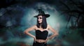 Young girl dressed as witch in misty forest on full moon night. Halloween fantasy Royalty Free Stock Photo