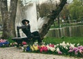 A young girl, dressed in a black jacket and a hat, sits alone on the bench Royalty Free Stock Photo