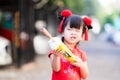 Young girl dressed in Chinese Cheongsam Qipao clothing. Happy child imaginative used a yellow umbrella.