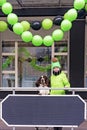 Young girl dressed in green jacket and hat and dog stands in front of window of decorated store, cafe Royalty Free Stock Photo
