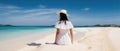 A young girl dressed in a white dress and hat stands with her back on the shore of a tropical island. Generative AI