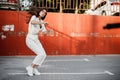 Young girl dressed in white shirt is dancing modern dance in the street against a painted concrete wall in the sunny day Royalty Free Stock Photo