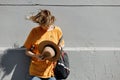 Young girl with dressed in a yellow t-shirt holds a straw hat in her hand stands leaning on a gray building in a city Royalty Free Stock Photo