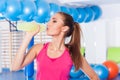 Young girl drinking isotonic drink, gym.