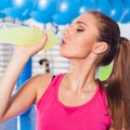 Young girl drinking isotonic drink, gym