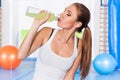 Young girl drinking isotonic drink, gym. She is happy Royalty Free Stock Photo