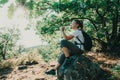 Girl drinking mineral water sitting on stone in forest. Hiker resting with aqua bottle during hike. Thirst quench beverage Royalty Free Stock Photo