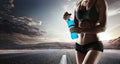 Young muscular build woman silhouette drinking water of bottle. Royalty Free Stock Photo