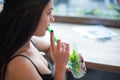 A young girl drinks a mojito through a straw while sitting in a cafe by the window. Royalty Free Stock Photo