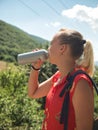 A young girl drinks water from a sports bottle outdoors on a blurred forest background. A woman quenches her thirst Royalty Free Stock Photo