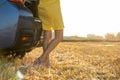 Young girl driver with slim legs in short yellow summer dress standing near her car on dry straw field Royalty Free Stock Photo