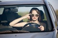 Young girl driving a car with a finger near her temple