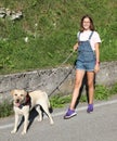 Young girl in dungarees walking the dog on a leash