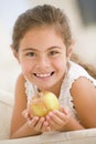 Young girl eating apple in living room smiling Royalty Free Stock Photo