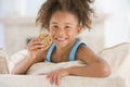 Young girl eating cookie in living room smiling Royalty Free Stock Photo