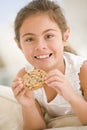 Young girl eating cookie in living room smiling Royalty Free Stock Photo