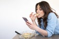 Young girl eating a piece of cake while using her smart phone Royalty Free Stock Photo