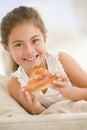 Young girl eating pizza slice in living room Royalty Free Stock Photo