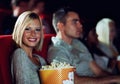 Me and my popcorn. A young girl eating popcorn while watching a movie at the cinema with her boyfriend. Royalty Free Stock Photo