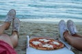 The young girl eats pizza on the beach, a dinner on the beach.