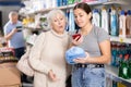Young girl and elderly woman scanning QR code on detergent in store