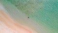 Young girl enjoying a beautiful beach shoreline. Crystal clear ocean water, downward view from drone