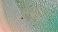 Young girl enjoying a beautiful beach shoreline. Crystal clear ocean water, downward view from drone